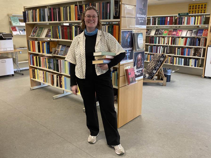 Line med en bogstak under armen på Skørping Bibliotek